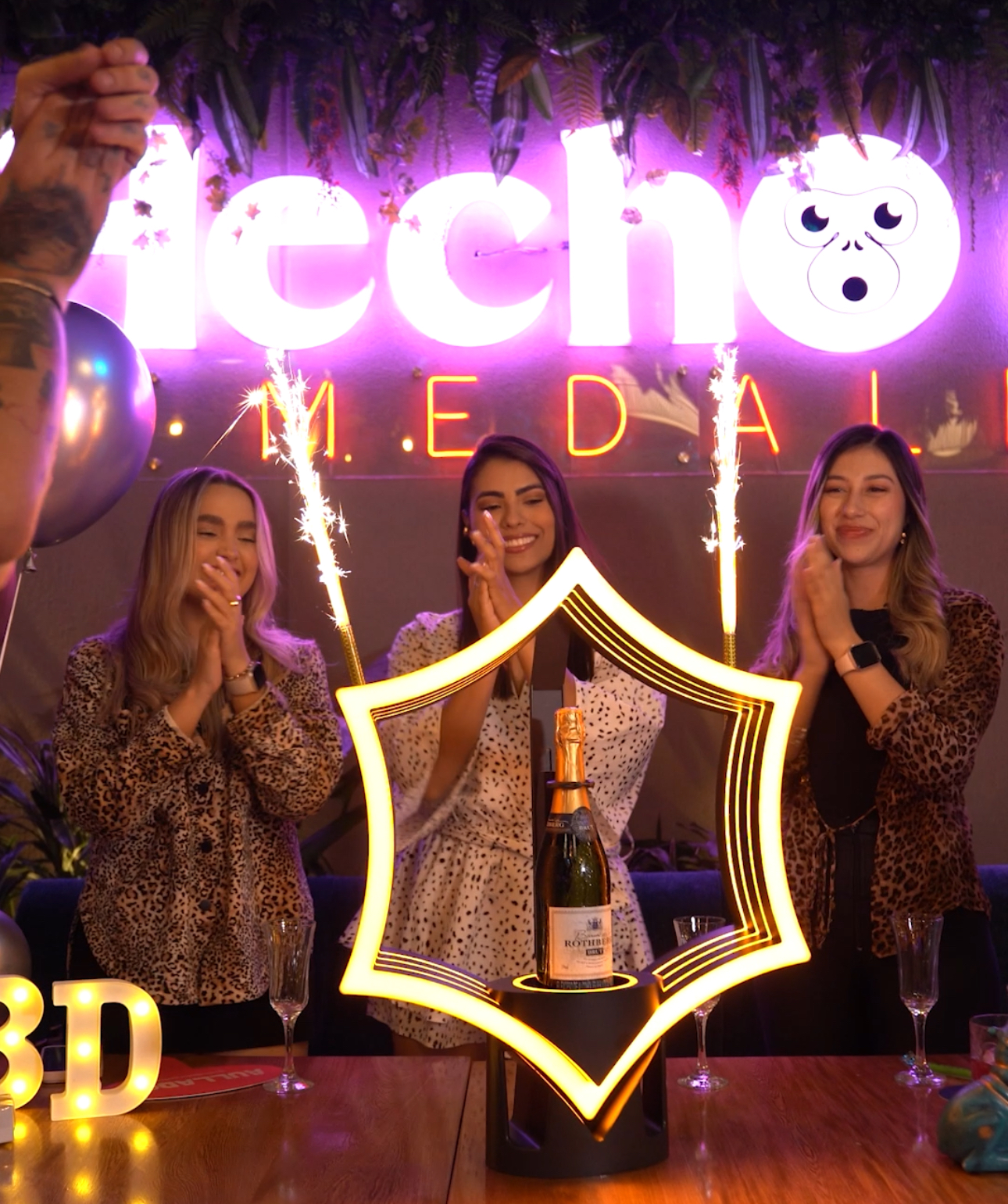 Celebración con letrero iluminado y champagne en Aullador